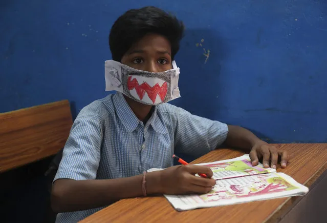 An Indian students wears a self-made mask and listens to a teacher at a government school in Hyderabad, India, Wednesday, March 4, 2020. A new virus first detected in China has infected more than 90,000 people globally and caused over 3,100 deaths. The World Health Organization has named the illness COVID-19, referring to its origin late last year and the coronavirus that causes it. (Photo by Mahesh Kumar A./AP Photo)