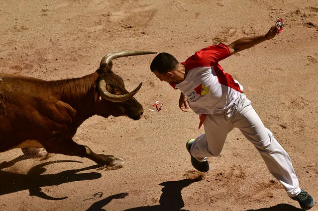A participant tries to place a ring in the horn of a bull during “Recortadores de Anillas” at the San Fermin Festival in Pamplona, northern Spain, Sunday, July 10, 2022. Revellers from around the world flock to Pamplona every year for nine days of uninterrupted partying in Pamplona's famed running of the bulls festival which was suspended for the past two years because of the coronavirus pandemic. (Photo by Alvaro Barrientos/AP Photo)