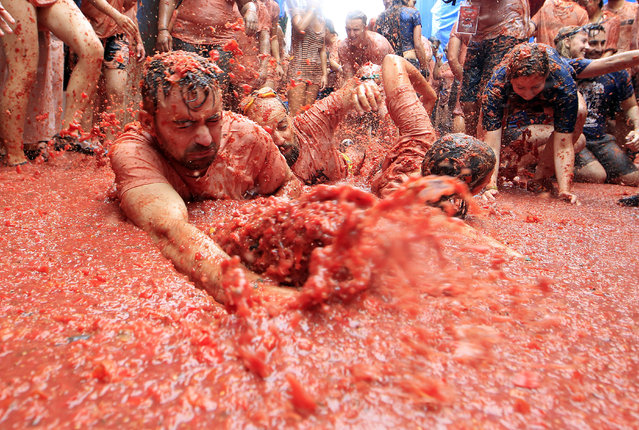 Revelers enjoy as they throw tomatoes at each other, during the annual “Tomatina”, tomato fight fiesta, in the village of Bunol, 50 kilometers outside Valencia, Spain, Wednesday, August 30, 2017. (Photo by Alberto Saiz/AP Photo)