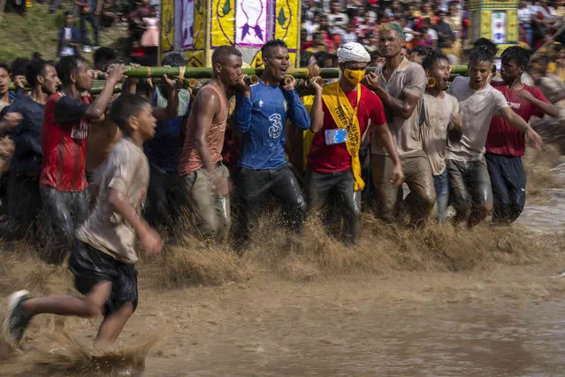 Pnar, or Jaintia, tribals carry “Rongs” or chariots and dance in muddy waters during Behdienkhlam festival celebrations in Tuber village, in the northeastern state of Meghalaya, India, Friday, July 22, 2022. Behdienkhlam is a traditional festival of the Pnars celebrated after sowing is done seeking a good harvest and to drive away plague and diseases. Young men symbolically drive away evil spirits by beating the roof of every house with bamboo poles. (Photo by Anupam Nath/AP Photo)