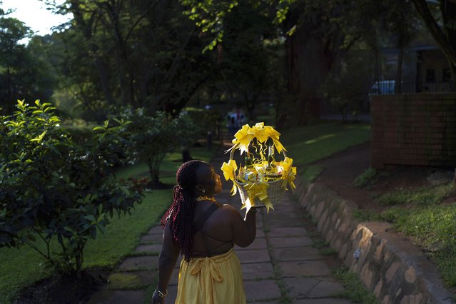 A woman carries a gift basket as she arrives to attend a friend's birthday party, at a park in Kampala, Uganda, November 24, 2024. (Photo by David Goldman/AP Photo)