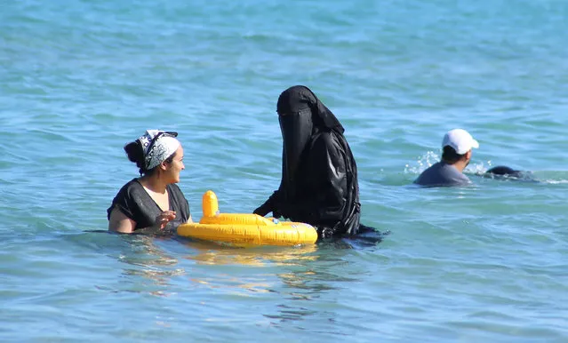 A woman wearing a niqab (C) cools off on the beach in Bizerte, Tunisia, July 21, 2016. (Photo by Zoubeir Souissi/Reuters)