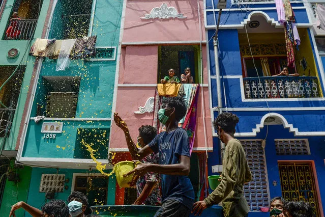 Volunteers throw a mixture of water, neem herb and turmeric as an alleged natural disinfectant on a street in a residential area during a government-imposed nationwide lockdown as a preventive measure against the COVID-19 coronavirus, in Chennai on April 7, 2020. (Photo by Arun Sankar/AFP Photo)