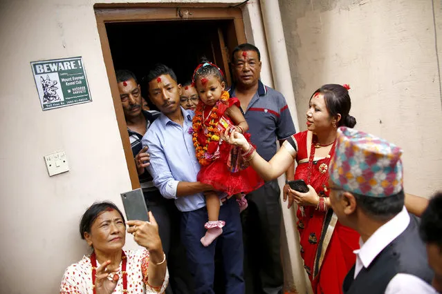 Nepal’s new living goddess Trishna Shakya, 3, is carried by her father as they leave home for a temple palace in Kathmandu, Nepal, Thursday, September 28, 2017. Shakya has become Nepal's new “Kumari”, revered by both Hindus and Buddhists in the Himalayan nation. She was carried in a religious ceremony to a temple palace in the heart of the Nepalese capital where she is to live until just before puberty. (Photo by Bikram Rai/AP Photo)