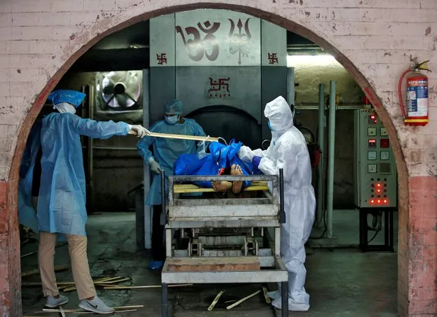 Municipal workers in protective gear prepare to cremate the body a man, who died due to coronavirus disease (COVID-19), at a crematorium in Ahmedabad, India, April 22, 2020. (Photo by Amit Dave/Reuters)