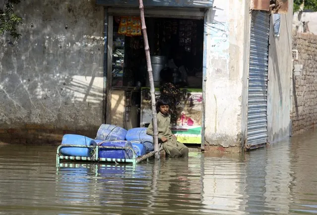 A victim of unprecedented flooding from monsoon rains sits in front a shop in Jaffarabad, Pakistan, Monday, September 5, 2022. (Photo by Fareed Khan/AP Photo)