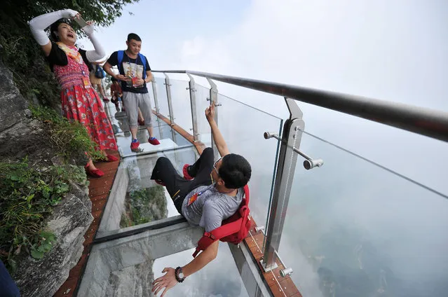 Tourists walk on the 100-meter-long and 1.6-meter-wide glass skywalk clung the cliff of Tianmen Mountain (or Tianmenshan Mountain) in Zhangjiajie National Forest Park on August 1, 2016 in Zhangjiajie, Hunan Province of China. (Photo by VCG/VCG via Getty Images)