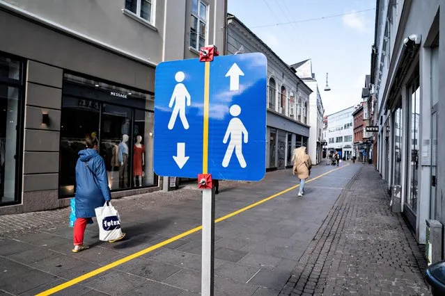 A painted yellow stripe divides a pedestrian street in the middle in order to help people to comply with the social distance guidelines amid the new corona pandemic on May 4, 2020 in Aalborg, Denmark. (Photo by Henning Bagger/Ritzau Scanpix/AFP Photo)