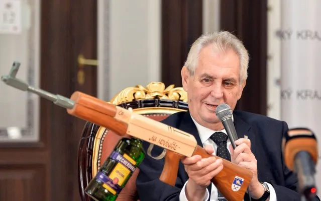 Czech President Milos Zeman holds a mock of submachine gun with the insription “At journalists” and a bottle of Becherovka liquor instead of the gunstock presented him at the press conference at the end of his visit to the Plzen Region in Zbiroh, about 65 km southwest of Prague, Friday, October 20, 2017. (Photo by Miroslav Chaloupka/CTK via AP Photo)