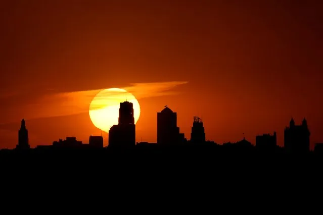 The sun sets behind downtown buildings, Sunday, September 25, 2022, in Kansas City, Mo. (Photo by Charlie Riedel/AP Photo)
