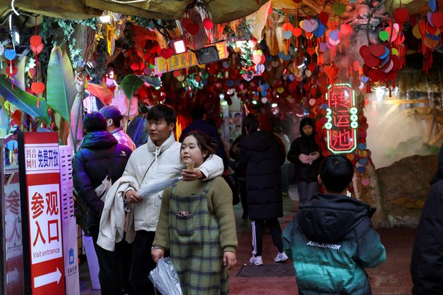 A couple walks out of a store entrance which is decorated with heart shaped ornaments in Shanghai, China, on February 14, 2025. (Photo by Go Nakamura/Reuters)