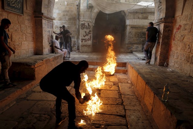 A Palestinian protester kicks a burning tyre during clashes between Palestinians and Israeli police officers in Jerusalem's Old City, September 15, 2015. (Photo by Ammar Awad/Reuters)