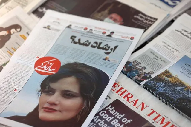 A newspaper with a cover picture of Mahsa Amini in Tehran, Iran, September 18, 2022. Police have said Amini fell ill as she waited with other women held by the morality police, who enforce strict rules in the Islamic republic requiring women to cover their hair and wear loose-fitting clothes in public. (Photo by Majid Asgaripour/WANA via Reuters)