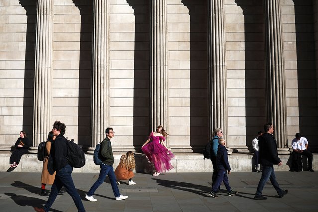 A woman poses for pictures in front of the Bank of England, in central London, on April 7, 2025. (Photo by Henry Nicholls/AFP Photo)