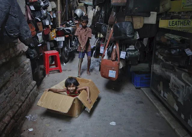 Children use a makeshift cardboard pail to play between the alley way of a market in Kolkata May 29, 2011. (Photo by Rupak De Chowdhuri/Reuters)