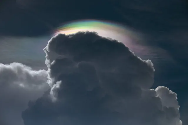 Cloud iridescence, an optical phenomenon where light is diffracted through water droplets, is pictured at the edge of clouds before a summer thunderstorm over Bangkok on May 28, 2020. (Photo by Alex Ogle/AFP Photo)