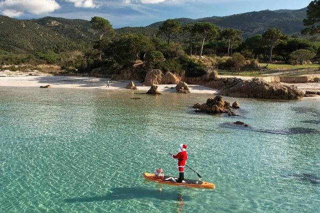 This aerial photograph shows a woman dressed as Santa Claus steering a paddleboard close to the Mare e Sol beach in Pietrosella on December 20, 2022 on the French Mediterranean island of Corsica. (Photo by Pascal Pochard-Casabianca/AFP Photo)