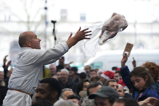 A butcher throws a turkey for sale to customers during the annual Christmas Meat Auction at Smithfield Market in London, Tuesday, December 24, 2024. (Photo by Kin Cheung/AP Photo)