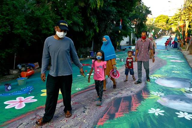 People wearing protective face masks walk past a mural depicting garden amid the coronavirus disease (COVID-19) outbreak in Jakarta, Indonesia, August 25, 2020. (Photo by Ajeng Dinar Ulfiana/Reuters)