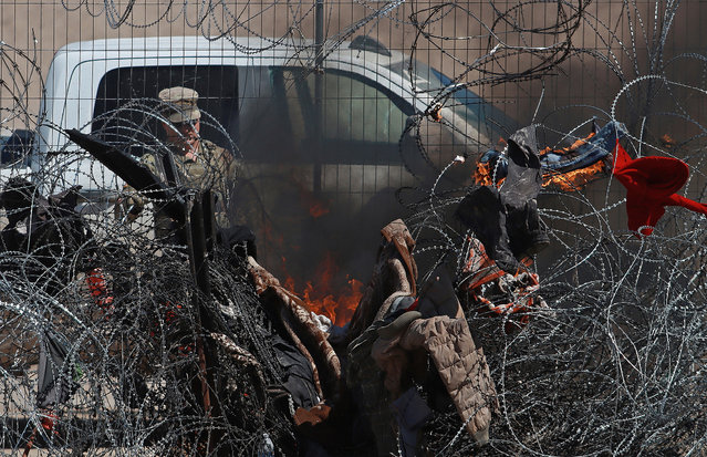 Members of the Texas National Guard set fire to clothing on a wire fence at the border that divides Mexico from the United States, in Ciudad Juarez, Mexico, 14 March 2024. The arbitrary arrests, robbery, extortion, sеxual violence, trafficking, and kidnapping against migrants arriving at the border of Ciudad Juarez provoked the intervention of the Mexican business community, which will invest almost $330,000 US dollars to support organizations that defend the mobile population. (Photo by Luis Torres/EPA/EFE)