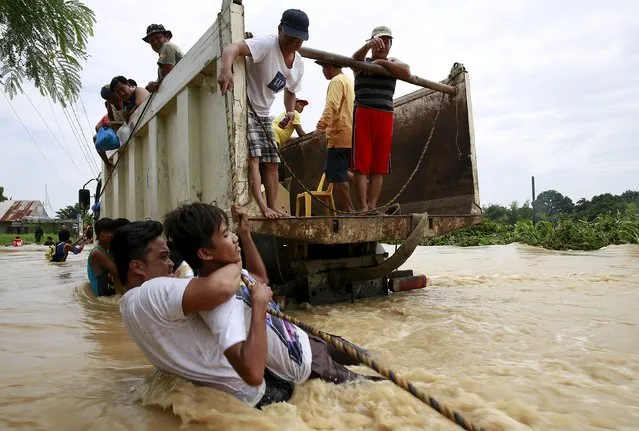 People hold a rope as they try to board a truck while crossing floodwaters brought by typhoon Koppu that battered Candaba town, Pampanga province, north of Manila October 20, 2015. (Photo by Romeo Ranoco/Reuters)