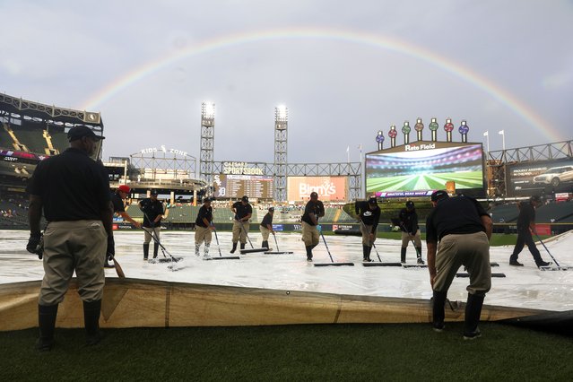 A rainbow appears over Rate Field as grounds crew squeegee water from a tarp before the start of a baseball game in Chicago, August 12, 2025. (Photo by Talia Sprague/AP Photo)