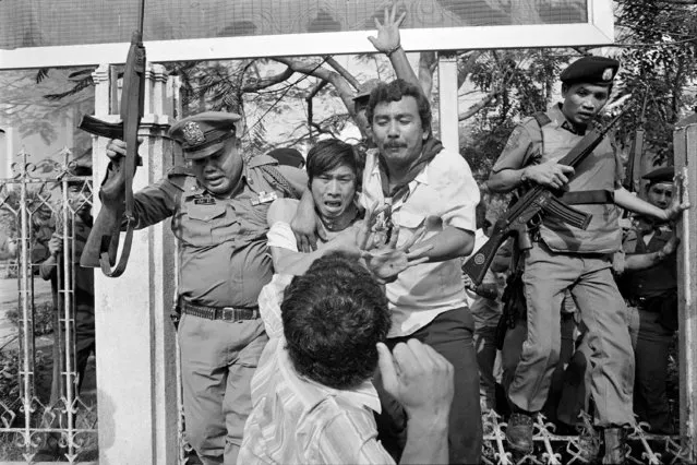 In this October 6, 1976 file photo a right-wing student, center foreground, draws his arm back to strike a captured and wounded leftist student being taken by police to an ambulance in Bangkok, Thailand. For some Thais, the bloody events of October 6, 1976 are still a nightmare. On that day, heavily armed security forces shot up Bangkok's Thammasat University campus and killed scores of students, while right-wing vigilantes captured would-be escapees, subjecting them to ghoulish lynchings. (Photo by Neal Ulevich/AP Photo)