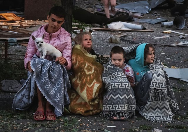 Residents sit at the site of an apartment building hit during Russian drone and missile strikes, amid Russia's attack on Ukraine, in Kyiv, Ukraine on August 28, 2025. (Photo by Reuters/Stringer)