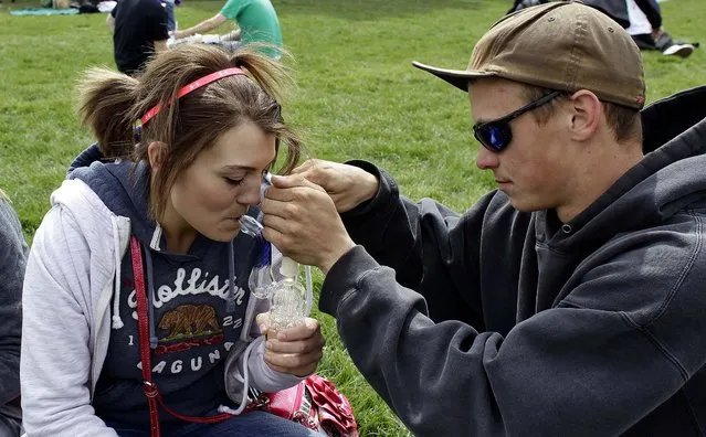 Carly, center, smokes marijuana with the help of Hunter, right, at the Denver 4/20 pro-marijuana rally at Civic Center Park in Denver on Saturday, April 20, 2013. (Photo by Brennan Linsley/AP Photo)