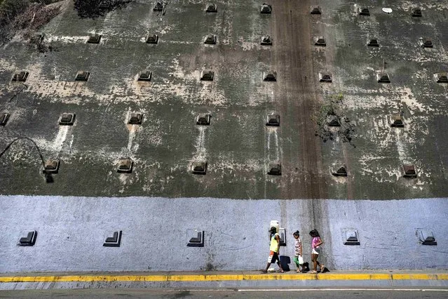 William Bermejo and his daughters carry containers with water collected from a mountain runoff near a highway tunnel in Caracas, Venezuela, March 19, 2023. (Photo by Matias Delacroix/AP Photo)