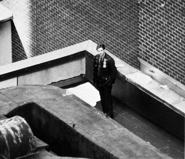 A New York City Police officer stands beside the covered body of 4 1/2-year-old Conor Clapton, son of rock guitarist Eric Clapton and Italian TV star Lori del Santo, who fell from a 53rd-floor window to the roof of a four-story building Wednesday, March 21, 1991. The boy's mother and housekeeper were in the apartment at the time he fell out the open window. (Photo by Ellis Kaplan/AP Photo)