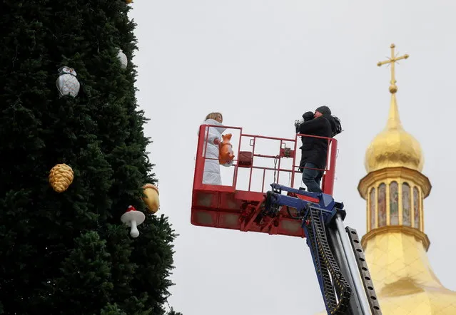 TV journalists report as municipal workers decorate a Christmas tree in front of St. Sofia Cathedral in central Kyiv, Ukraine, December 8, 2020. (Photo by Gleb Garanich/Reuters)