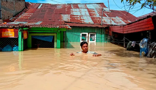 This picture taken on November 28, 2020 shows a man leaving his flooded house in Tebing Tinggi, as thousands of houses were inundated in North Sumatra after torrential rains pounded the area. (Photo by Ahmad Putra/AFP Photo)