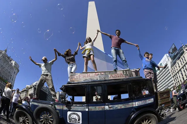 Argentinian Zapp family wave on top of their car, a 1928 Graham-Paige, at Republica square in Buenos Aires, on March 13, 2022 after finishing a 22 year-journey arround the world that started on January 23, 2000. (Photo by Juan Mabromata/AFP Photo)