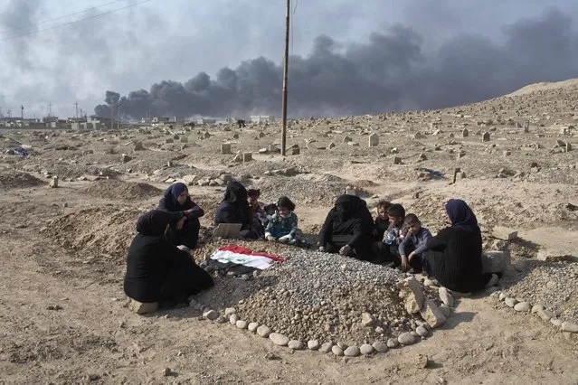 A family grieves over a grave of a family member at a graveyard damaged by Islamic State extremists in Qayara, some 31 miles, 50 km, south of Mosul, Iraq, Thursday, October 27, 2016. When IS overran Qayara more than two years ago, the extremist group began destroying headstones at the local graveyard, telling residents they were forbidden because they did not exist at the time of the prophet. (Photo by Marko Drobnjakovic/AP Photo)