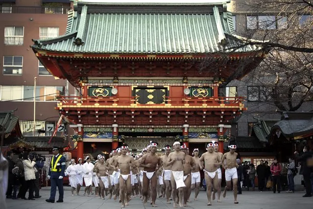 Shrine parishioners run in front of the gate before pouring cold water onto themselves during an annual cold-endurance festival at the Kanda Myojin Shinto shrine in Tokyo, Saturday, January 10, 2015. (Photo by Eugene Hoshiko/AP Photo)