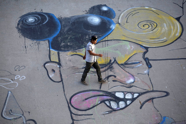 A man walks over a graffiti mocking U.S. President Donald Trump at the Mexican side of the border in Ciudad Juarez, Mexico April 4, 2018. (Photo by Jose Luis Gonzalez/Reuters)