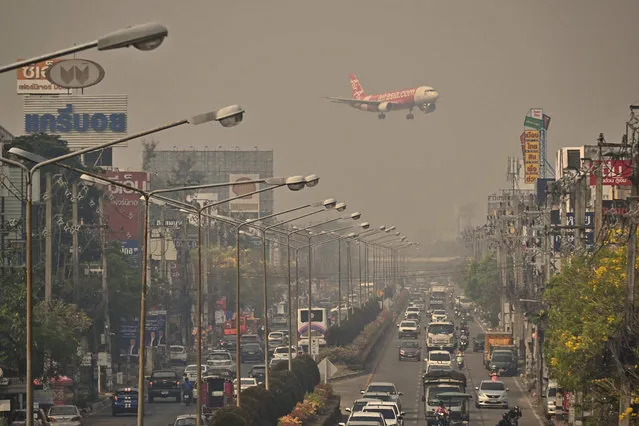 An Air Asia plane descends towards Chiang Mai International Airport amid high levels of air pollution in Chiang Mai on April 10, 2023. (Photo by Lillian Suwanrumpha/AFP Photo)