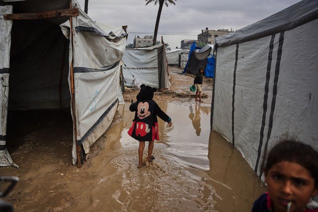 A Palestinian walks through a mud puddle at a temporary tent encampment flooded by a heavy rainfall in Deir al-Balah, central Gaza Strip, November 25, 2025. (Photo by Abdel Kareem/AP Photo)
