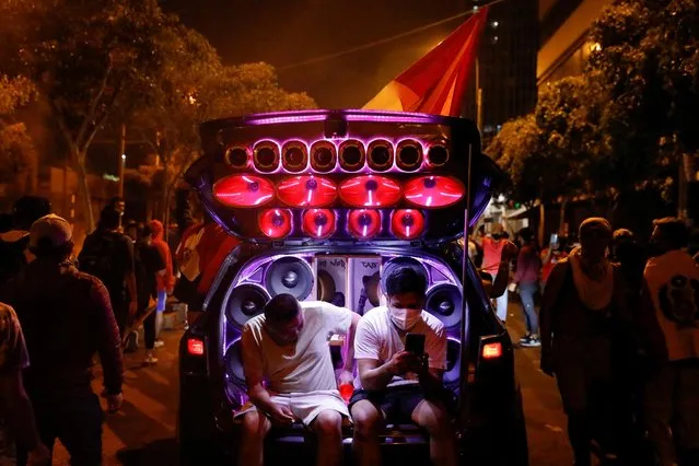 People listen to music while sitting on the back of a car during a protest against Peru's President Pedro Castillo after he had issued a curfew mandate which was lifted following widespread defiance on the streets, as protests spiraled against rising fuel and fertilizer prices triggered by the Ukraine conflict, in Lima, Peru on April 5, 2022. (Photo by Alessandro Cinque/Reuters)
