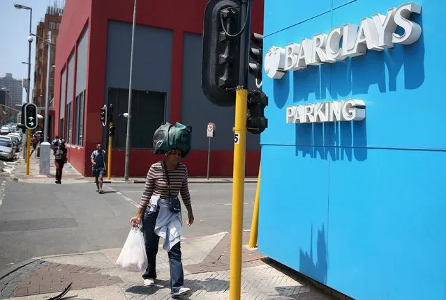 A women carries her belongings on her head as she walks past a Barclays logo in Johannesburg December 16, 2015. (Photo by Siphiwe Sibeko/Reuters)