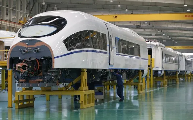 An employee works on a final assembly line for CRH380B, a high speed train model, at China CNR's Tangshan Railway Vehicle's factory in Tangshan, Hebei province, February 11, 2015. China CNR, one of the country's top trainmakers, said it was interested in buying foreign rail-linked technologies as China seeks to export its high-speed trains and rail expertise. (Photo by Kim Kyung-Hoon/Reuters)