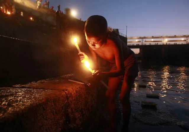 A Hindu devotee lights candles after taking a holy dip in the waters of river Howrah during the Makar Sankranti festival on the outskirts of Agartala, capital of India's northeastern state of Tripura, January 15, 2015. Makar Sankranti is an auspicious festival celebrated by Hindus across the country that marks the start of the harvest season. (Photo by Jayanta Dey/Reuters)