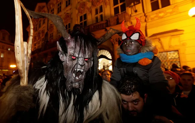 A man and his child look at reveller dressed as a devil, on the eve of Saint Nicholas Day, at the Old Town Square in Prague, Czech Republic December 5, 2016. (Photo by David W. Cerny/Reuters)