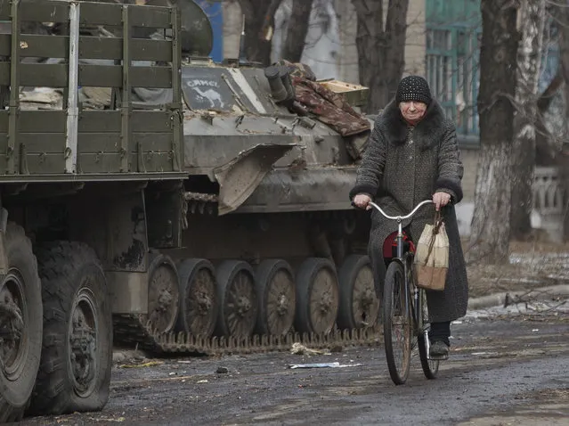 A resident rides a bicycle passing by an armored vehicle in Debaltseve, Ukraine, Friday, Feb. 20, 2015. After weeks of relentless fighting, the embattled Ukrainian rail hub of Debaltseve fell Wednesday to Russia-backed separatists, who hoisted a flag in triumph over the town. The Ukrainian president confirmed that he had ordered troops to pull out and the rebels reported taking hundreds of soldiers captive.(AP Photo/Vadim Ghirda)
