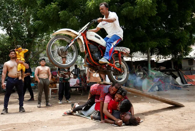 A Hindu devotee performs a stunt with his motorcycle during a rehearsal ahead of the annual Rath Yatra, or chariot procession, in Ahmedabad, India on June 22, 2022. (Photo by Amit Dave/Reuters)