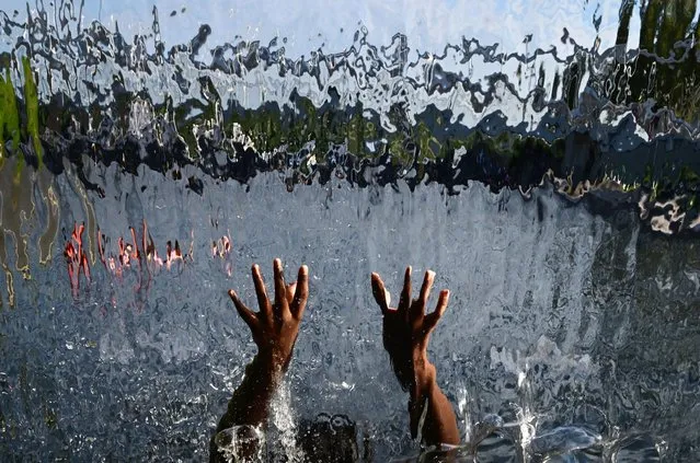 A child cools off in a waterfall feature at the Yards Park on Monday September 04, 2023 in Washington, DC. The area saw temperatures rise to the 90’s. (Photo by Matt McClain/The Washington Post)