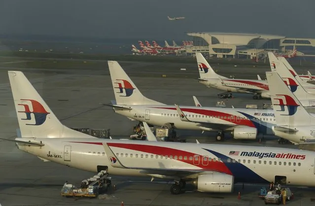 Ground crew work among Malaysia Airlines planes on the runway at Kuala Lumpur International Airport (KLIA) in Sepang July 25, 2014. The 19,500 staff of Malaysia Airlines (MAS) face a new ordeal - a quarter of them may lose their jobs at the unprofitable airline, hit by two jet disasters this year. Flight MH370 remains untraced since its disappearance en route from Kuala Lumpur to Beijing in March. Picture taken July 25, 2014. To match MALAYSIA-AIRLINES/STAFF REUTERS/Olivia Harris
