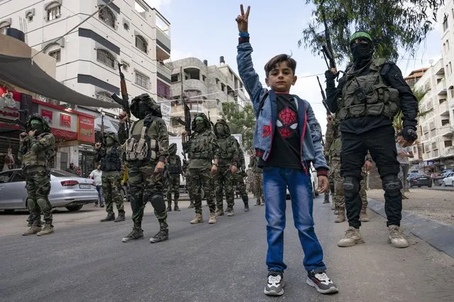 Children stand with Hamas militants as they parade through the streets for Bassem Issa, a top Hamas' commander, who was killed by Israeli Defense Force military actions prior to a cease-fire reached after an 11-day war between Gaza's Hamas rulers and Israel, in Gaza City, Saturday, May 22, 2021. (Photo by John Minchillo/AP Photo)