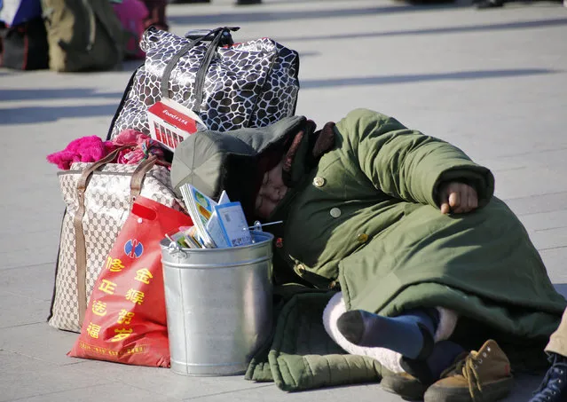 A woman takes a nap next to her luggage in front of the Beijing Railway Station during the travel rush ahead of the upcoming Spring Festival in Beijing, China, February 2, 2016. (Photo by Kim Kyung-Hoon/Reuters)